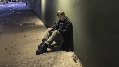 Photo of A wealthy man publicly demeaning a young boy working as a shoe shiner beneath an underpass